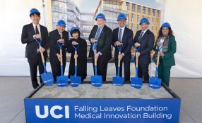 Group of leaders holding shovels behind the Falling Leaves Foundation Medical Innovation Building sign