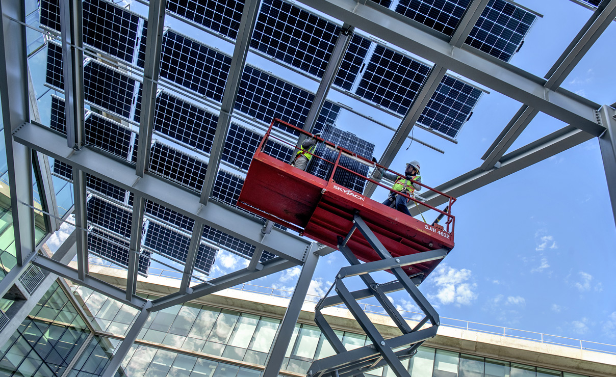 Worker installing solar panel outside COHS building